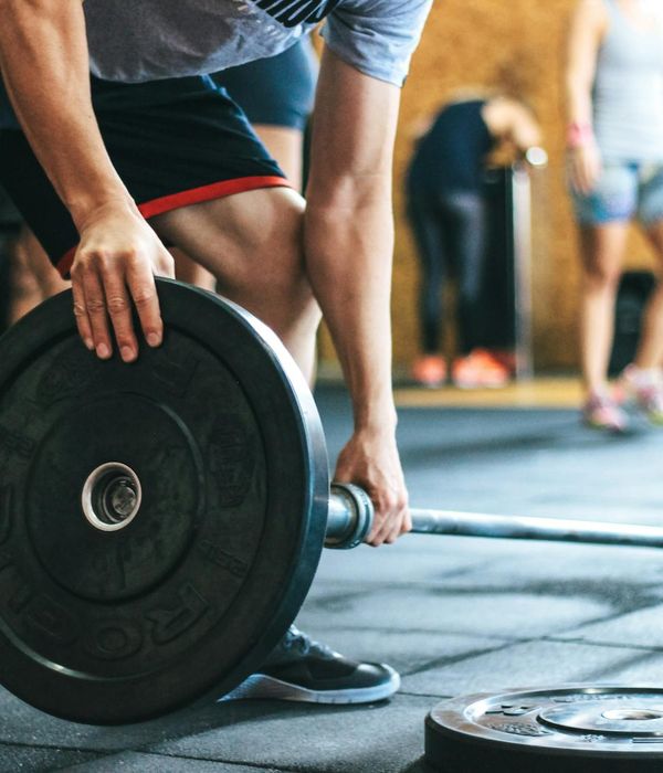 Strong man performing a weightlifting exercise in a gym setting
